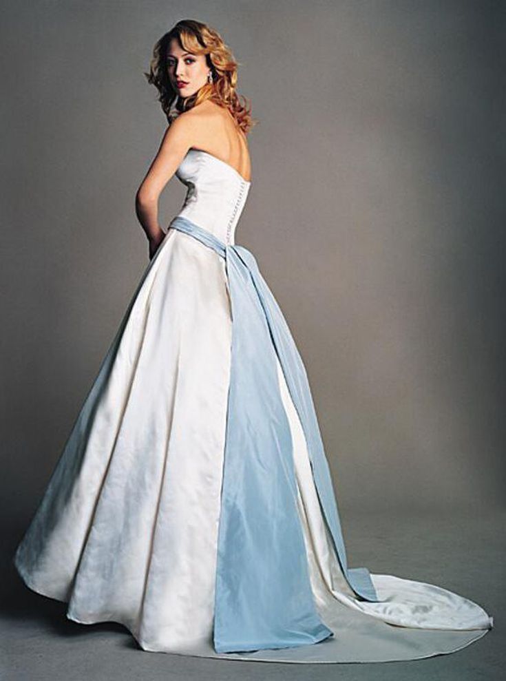 a woman in a white and blue wedding dress posing for a photo with her hands on her hips