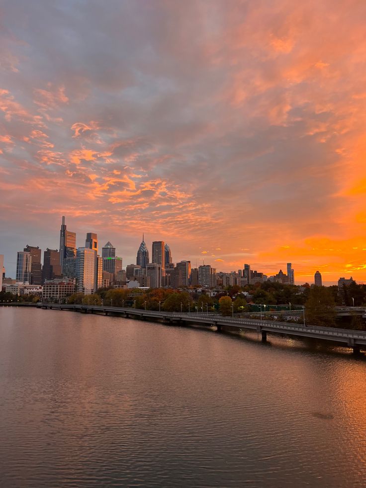 the sun is setting over a large city and it's reflection in the water