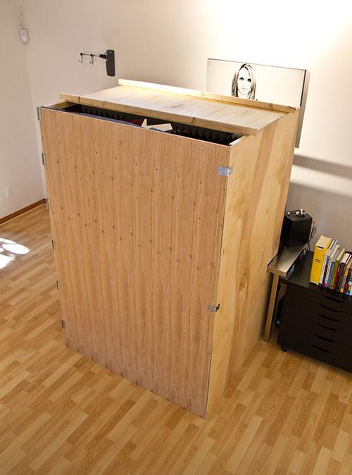 a room with hard wood flooring and a large wooden storage unit in the corner