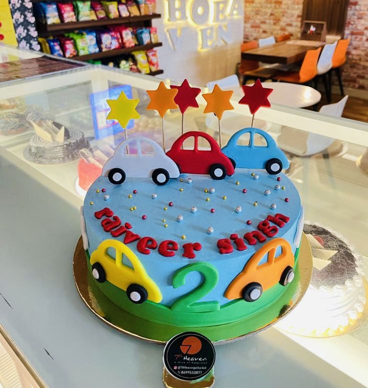 a birthday cake with cars and stars on top is sitting on a counter in a store