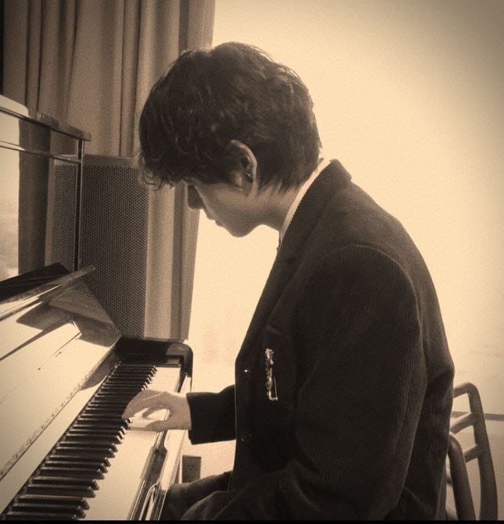 a young man is playing the piano in his living room