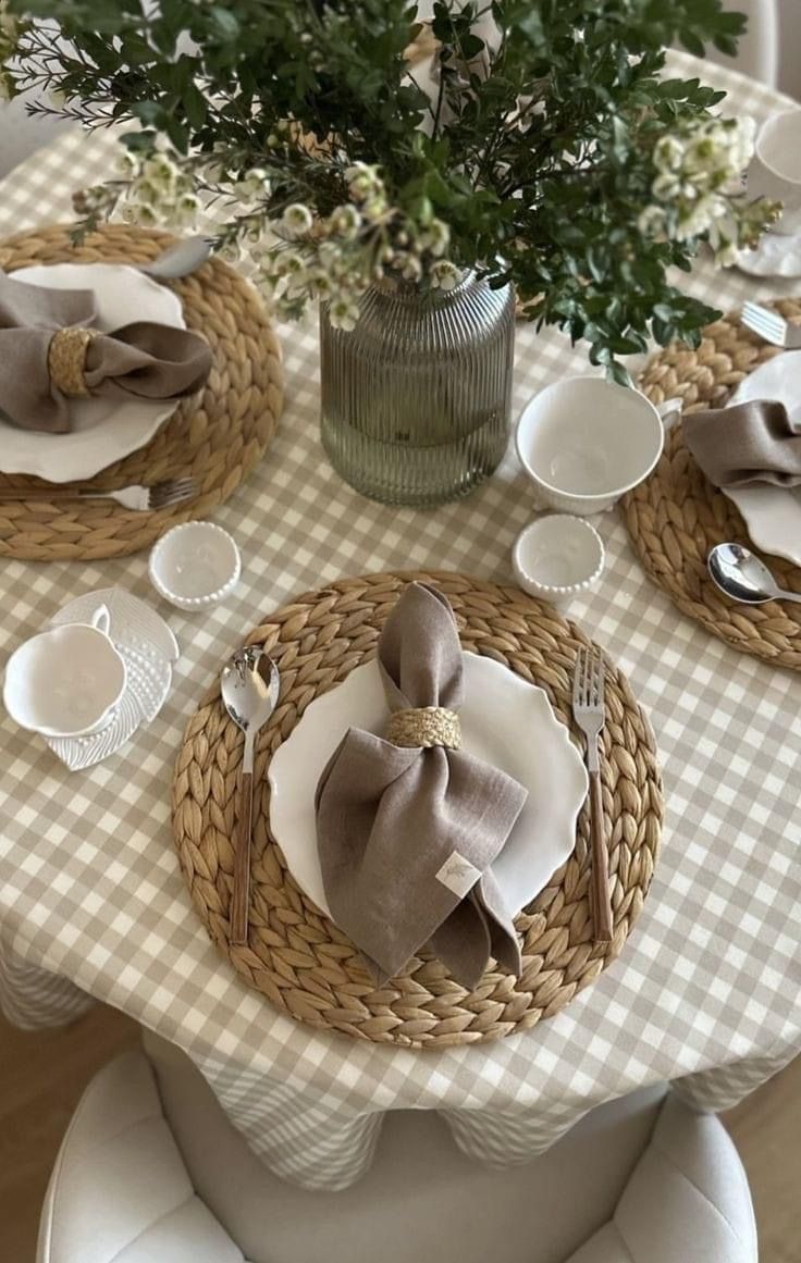 the table is set with plates and silverware, napkins and flowers in a vase