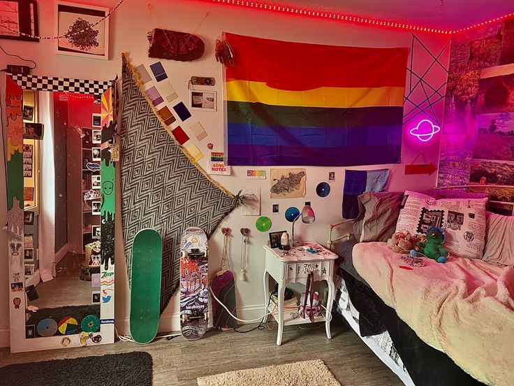 a bedroom with a bed, desk and rainbow flag hanging on the wall above it