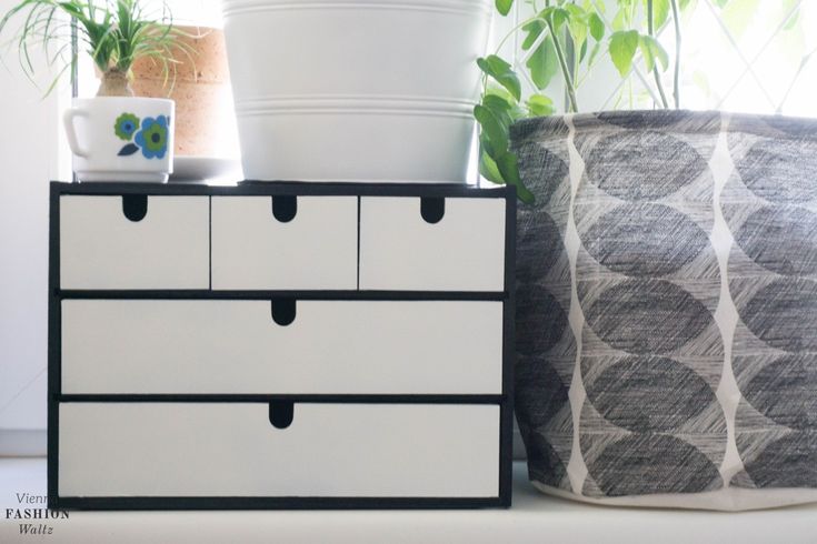 two planters are sitting next to each other on top of a white dresser with black drawers