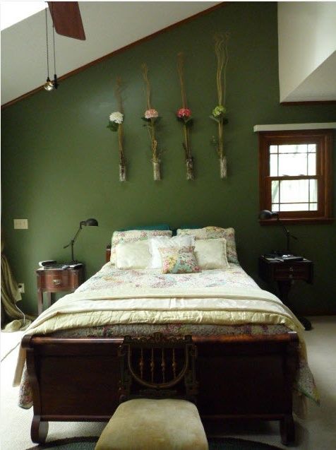 a bed sitting in a bedroom next to a wall with hanging flowers on the walls