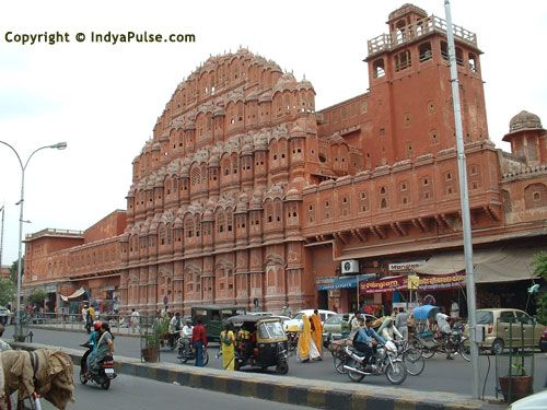 people are walking and riding bikes in front of a large building with many stories on it