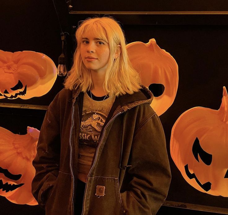 a woman standing in front of carved pumpkins