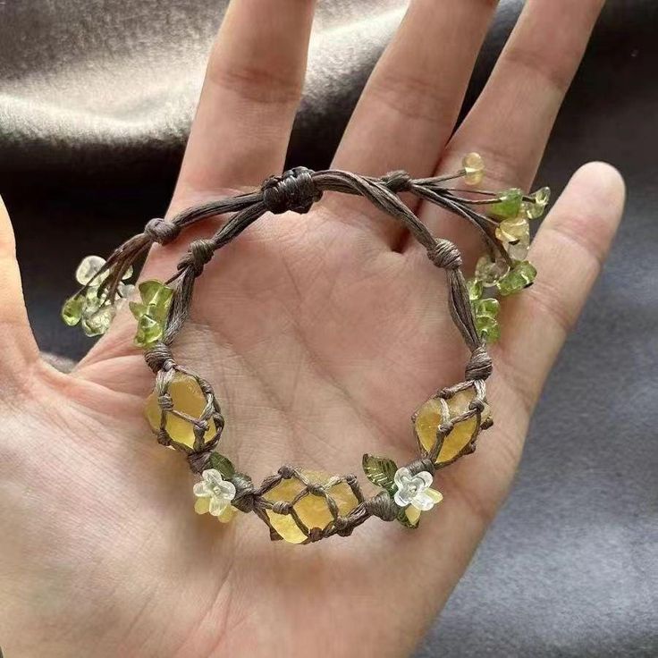 a hand is holding a bracelet with green and yellow glass beads on it's wrist