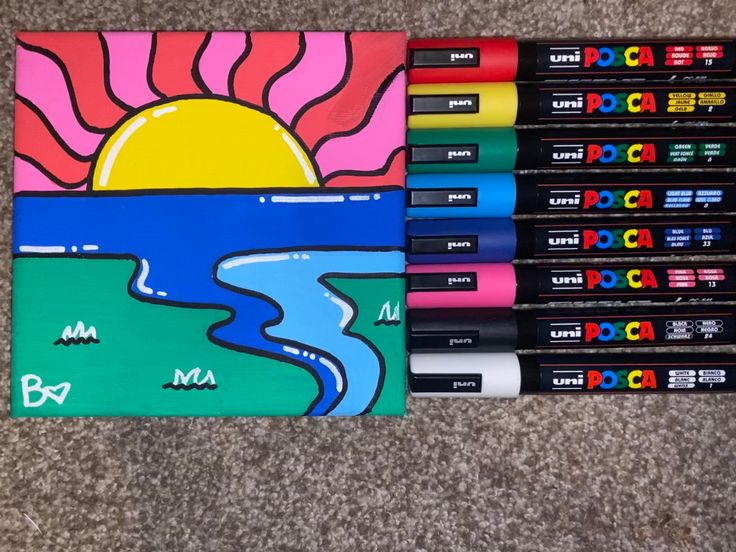 several different colored markers sitting next to each other on the floor with an image of a sunset