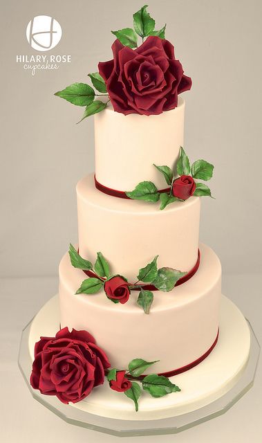 a three tiered cake with red roses on it