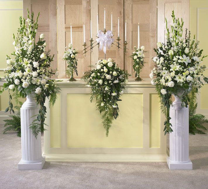 three tall white vases with flowers and greenery