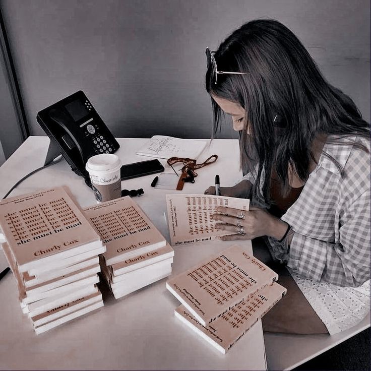 a woman sitting at a desk with stacks of books