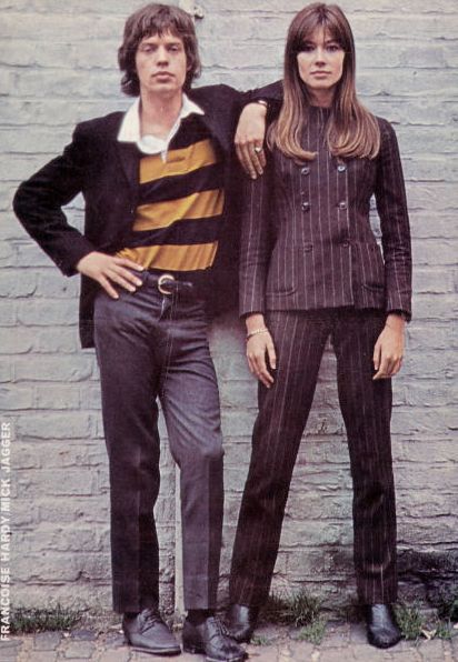 two women and one man are standing in front of a brick wall with their hands on their hips