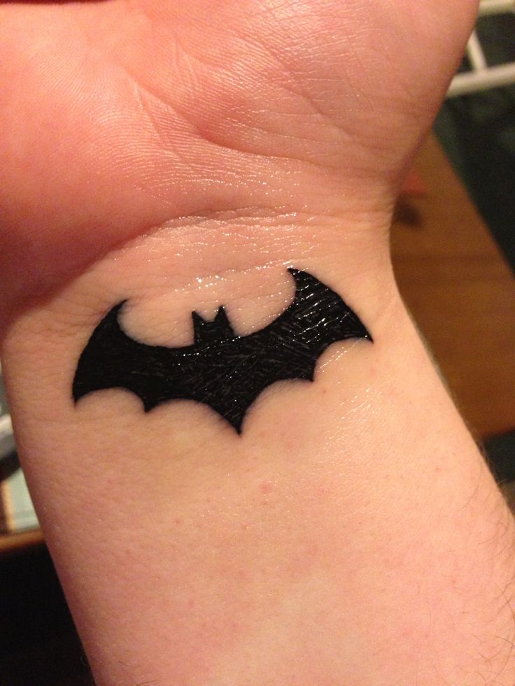 a small tattoo on the wrist of a person with a bat symbol tattooed on it