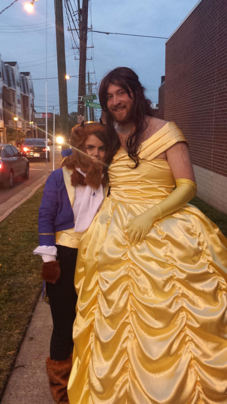 a man and woman dressed up as princesses pose for a photo on the sidewalk