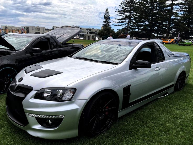 two silver cars parked on top of a lush green field