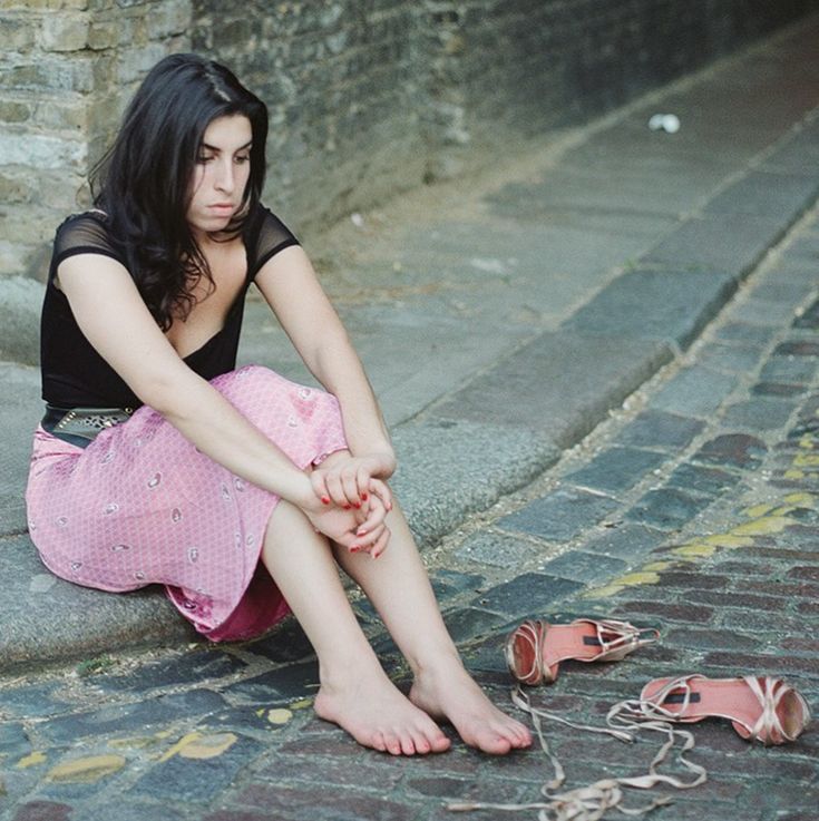 a woman sitting on the ground next to shoes