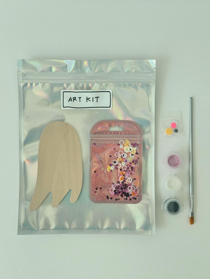 an art kit in a clear plastic bag with paint, brushes and paper angel wings