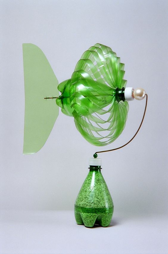 a green vase sitting on top of a table next to a light bulb and a lamp