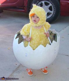 a child dressed as a chicken in an egg costume