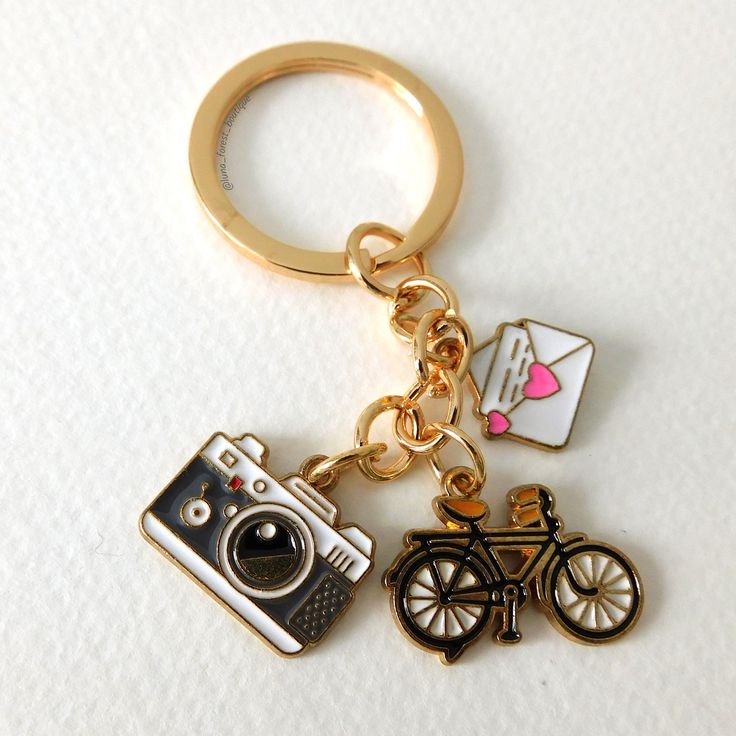 a gold key chain with two different items on it, one is a camera and the other has an instagram sticker