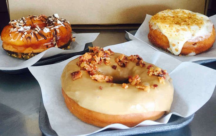 three donuts with different toppings sitting on top of a table next to each other