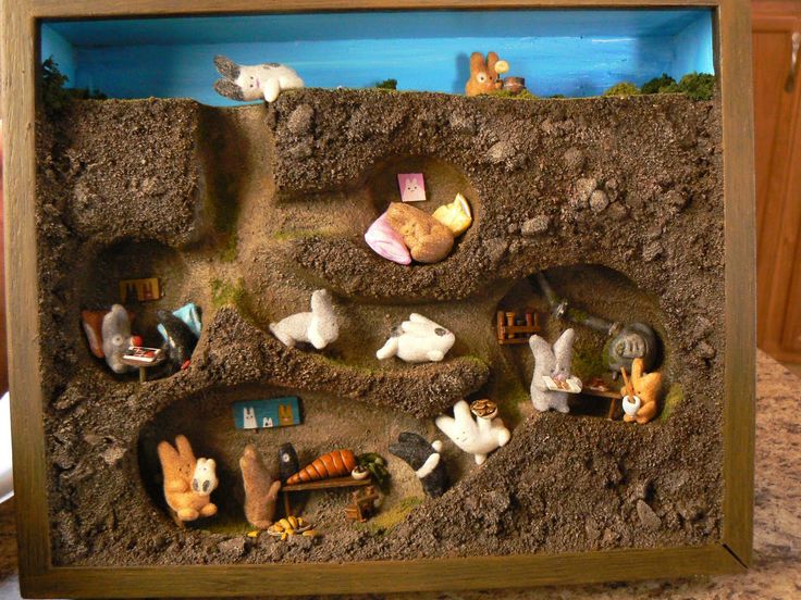 a wooden frame with many different animals in the sand and on top of it is a fake house