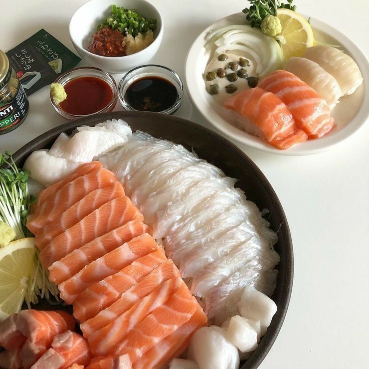 two plates filled with different types of sushi and sauces on top of them