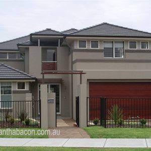 two story house with red garage doors and black fence