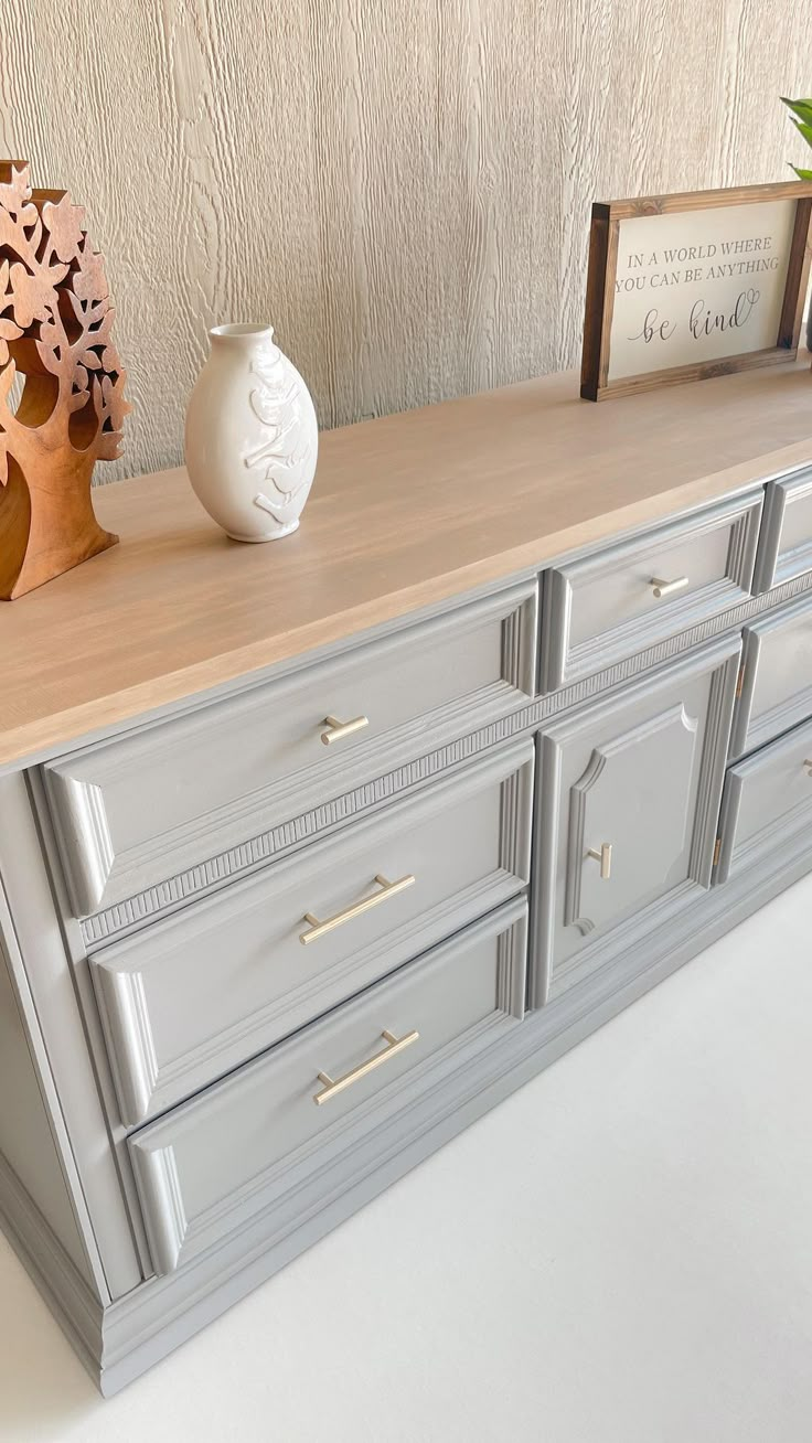 a white vase sitting on top of a dresser next to a wooden shelf with drawers