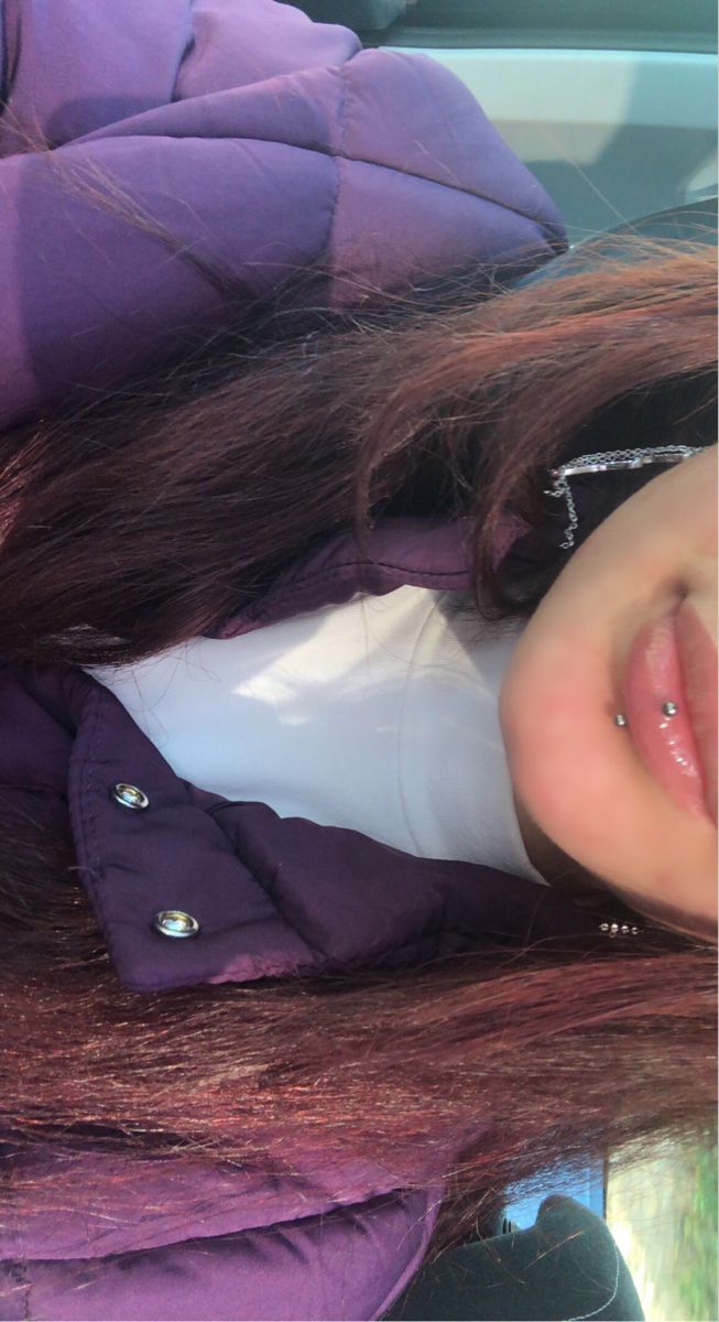 a girl with long hair is smiling for the camera while wearing a purple jacket and white shirt