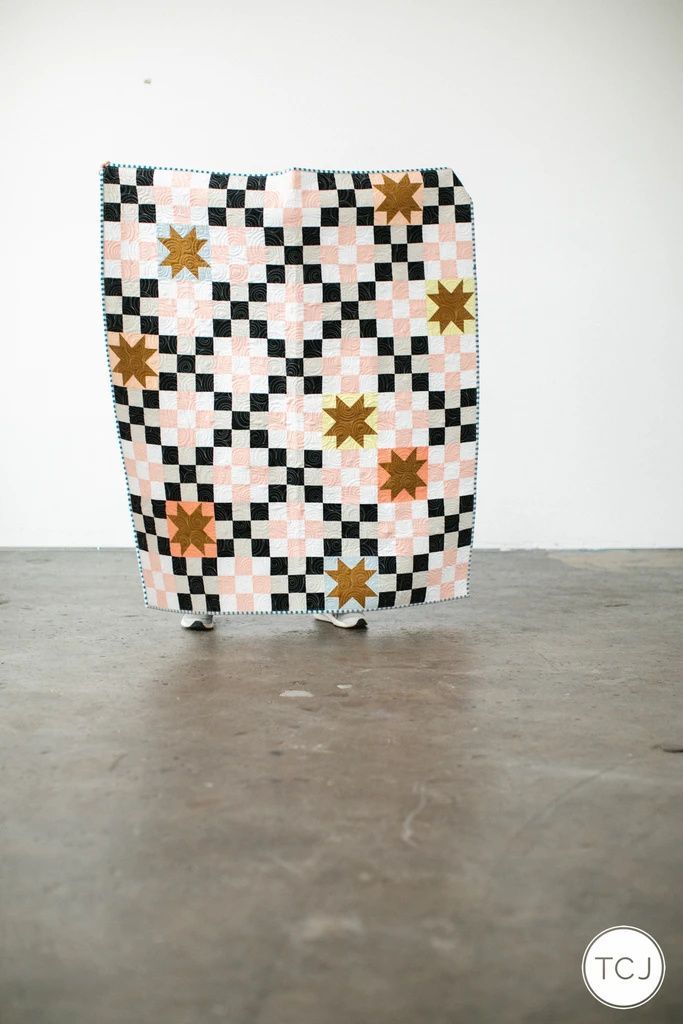 a black and white checkered bag with gold stars on the front sitting on a table