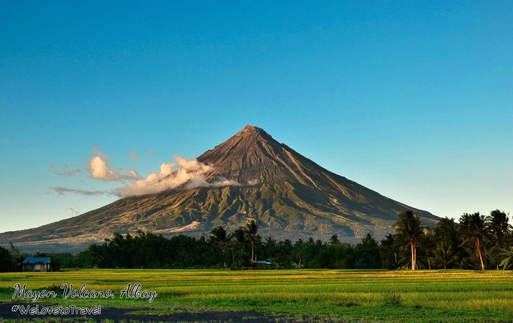 a large mountain towering over a lush green field