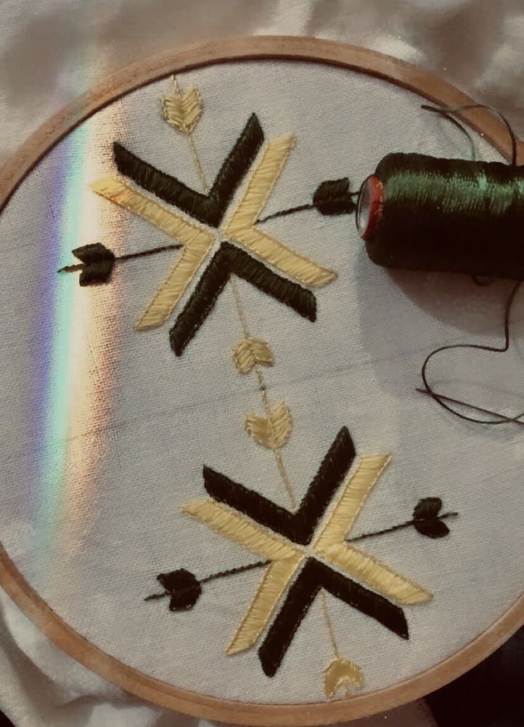 a close up of a piece of embroidery on a table with a spool of thread