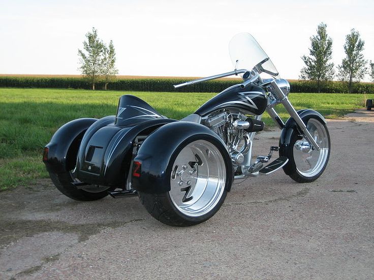 a black motorcycle parked on top of a road next to a lush green grass covered field