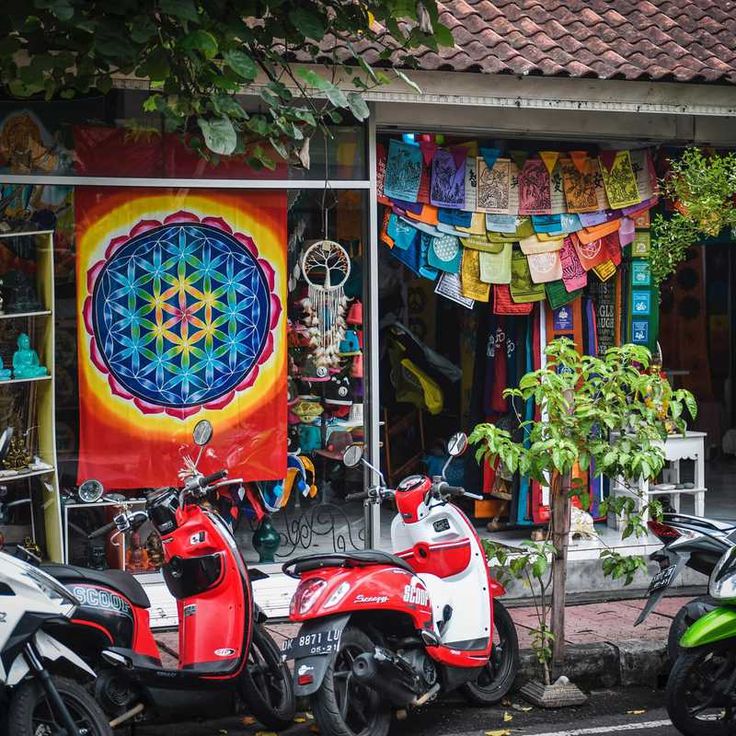 several scooters parked in front of a shop with colorful artwork on the walls