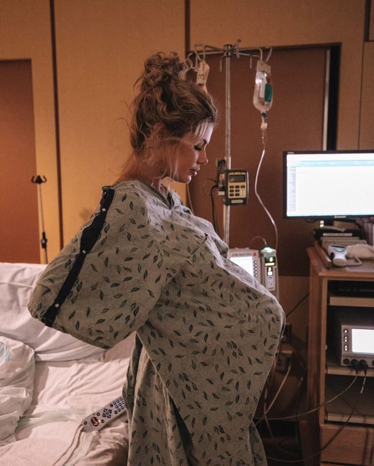 a woman standing in a hospital room next to a monitor