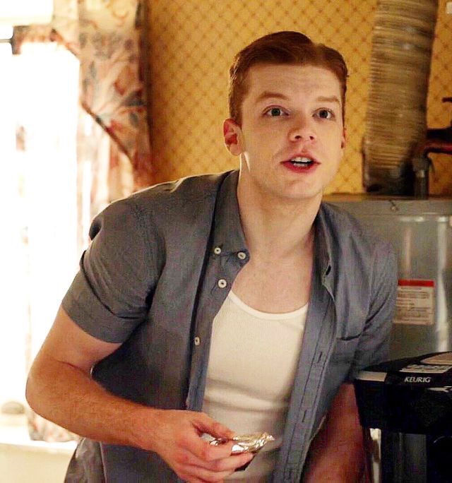 a man standing in front of a toaster oven holding a piece of food and looking at the camera