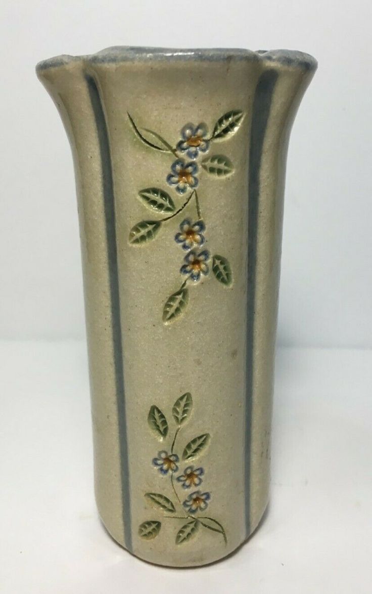 a white vase with blue and yellow flowers painted on the side is sitting on a table