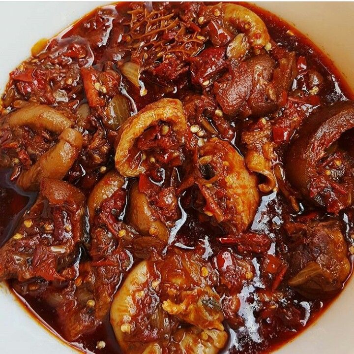 a white bowl filled with meat and mushrooms covered in marinade sauce on top of a wooden table