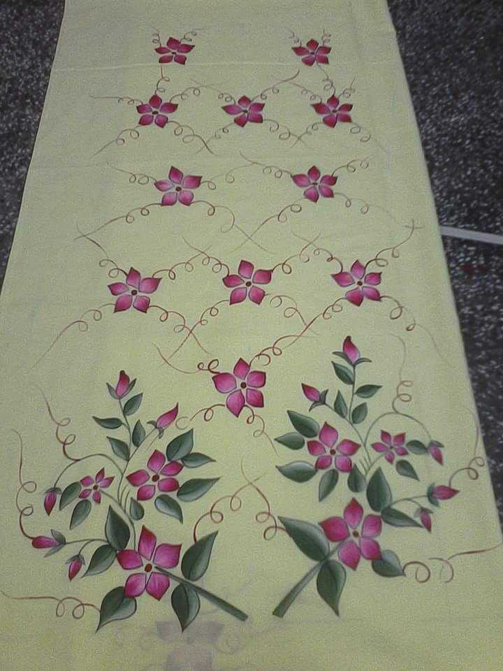 a table runner with pink flowers and green leaves on yellow ground next to black carpet