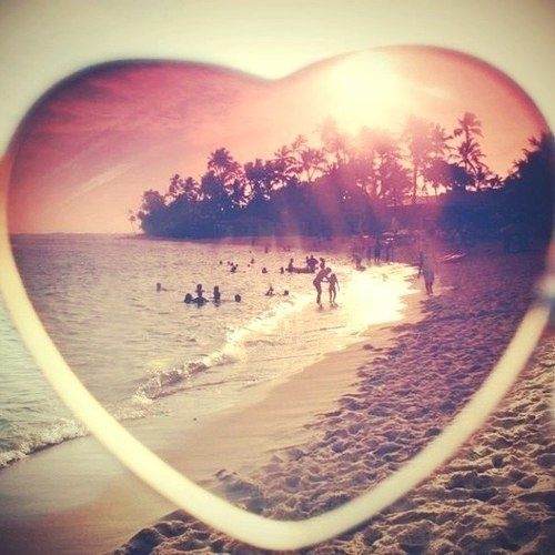 a heart - shaped frame with people swimming in the ocean at sunset on a beach