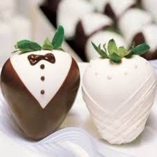 two chocolate covered strawberries are sitting on a table with other desserts in the background