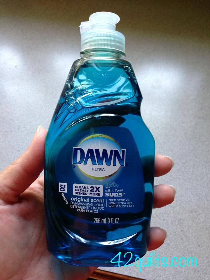 a hand holding a bottle of dawn liquid