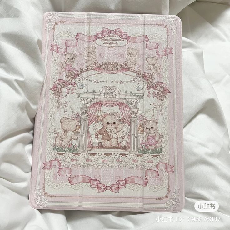 a cross stitch book with teddy bears on the front and back cover, sitting on a bed