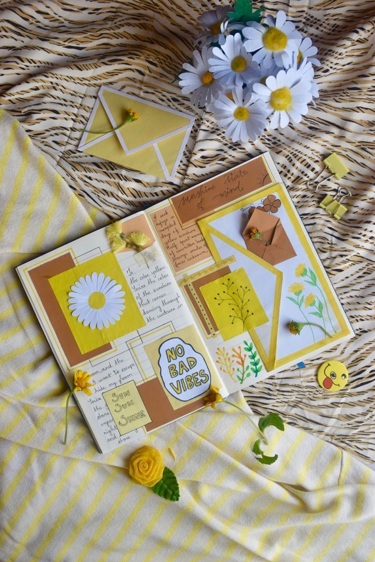 a close up of a book on a bed with flowers in the background and paper