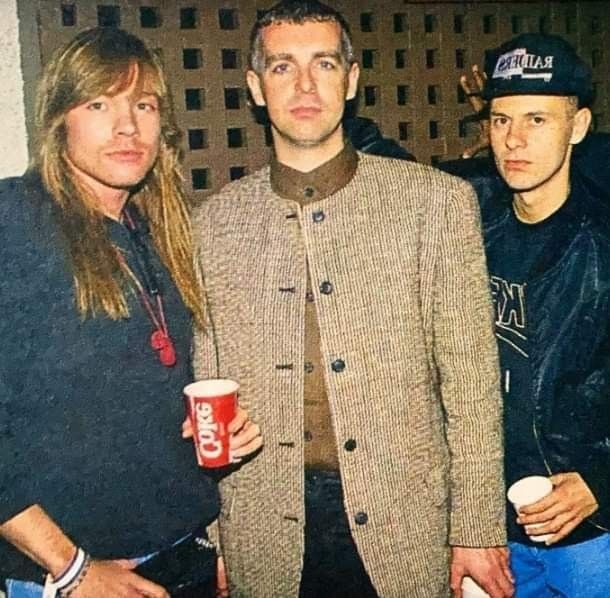 three people standing next to each other with cups in their hands and one person holding a drink