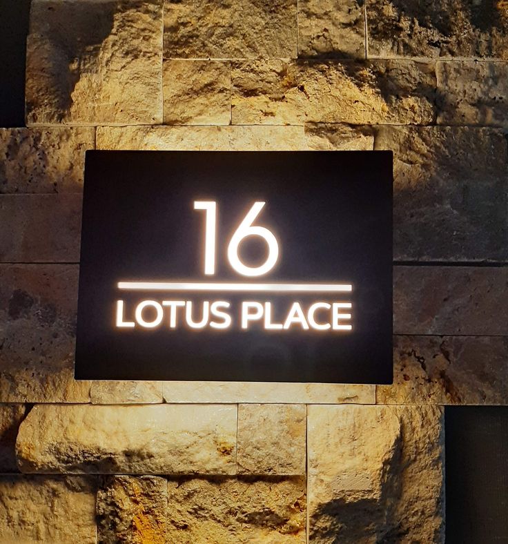 a sign that reads 16 lotus place in front of a stone wall with the number sixteen on it