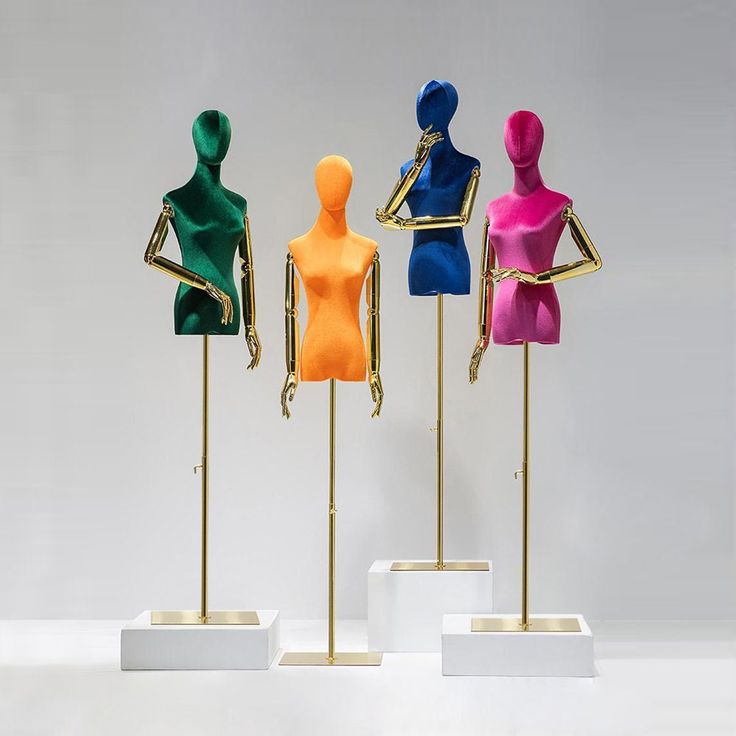 three mannequins with different colored tops on display in a white room next to each other