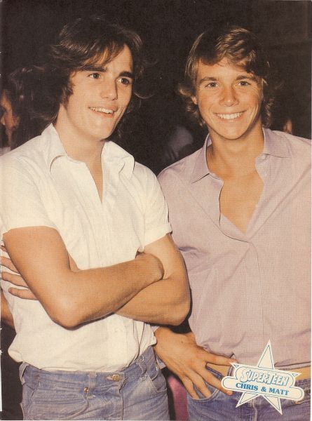 two young men standing next to each other with their arms crossed and smiling at the camera